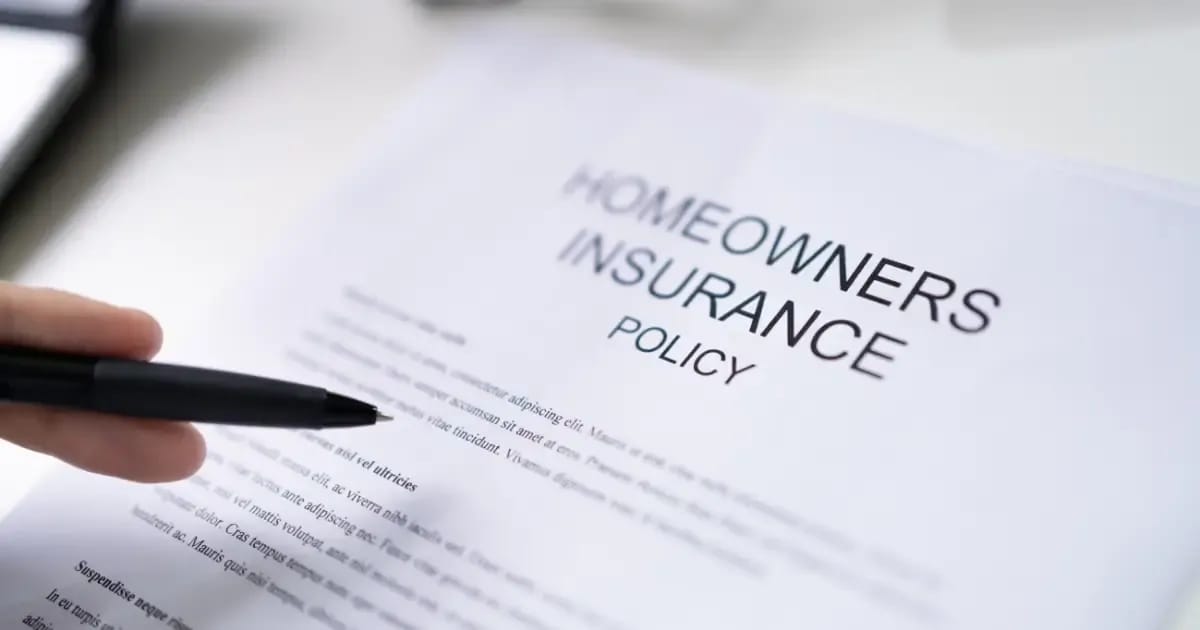A hand holding a pen over a homeowner's insurance policy document 
